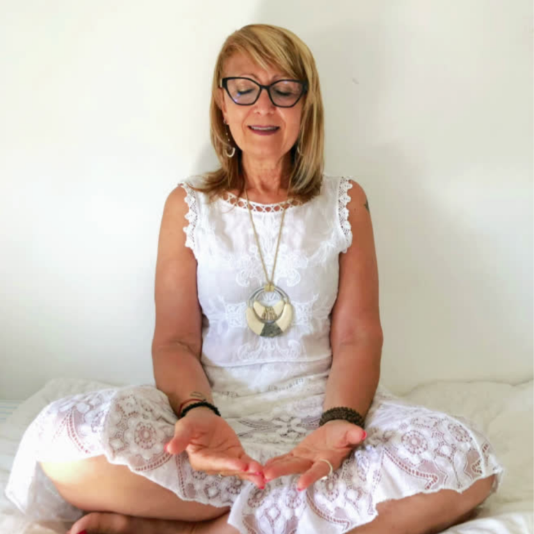 Puri Duque sentada meditando, con los ojos cerrados y las manos abiertas
